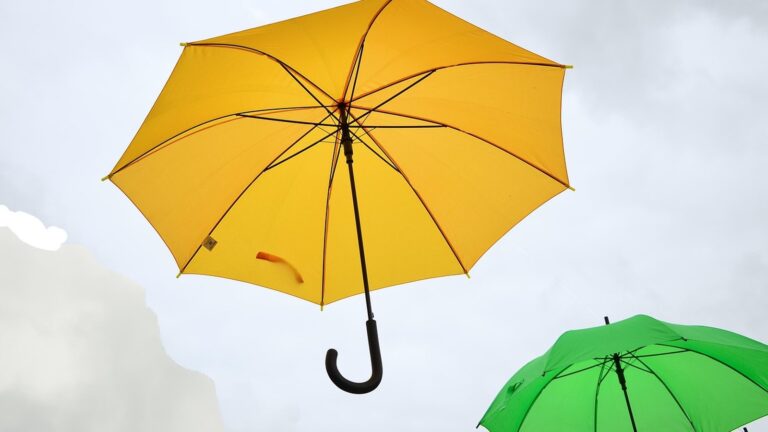 Žlutý otevřený deštník proti zatažené obloze